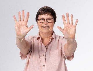 Жена, вдигаща ръцете си към камерата, за да покаже пълната липса на убождания на пръстите